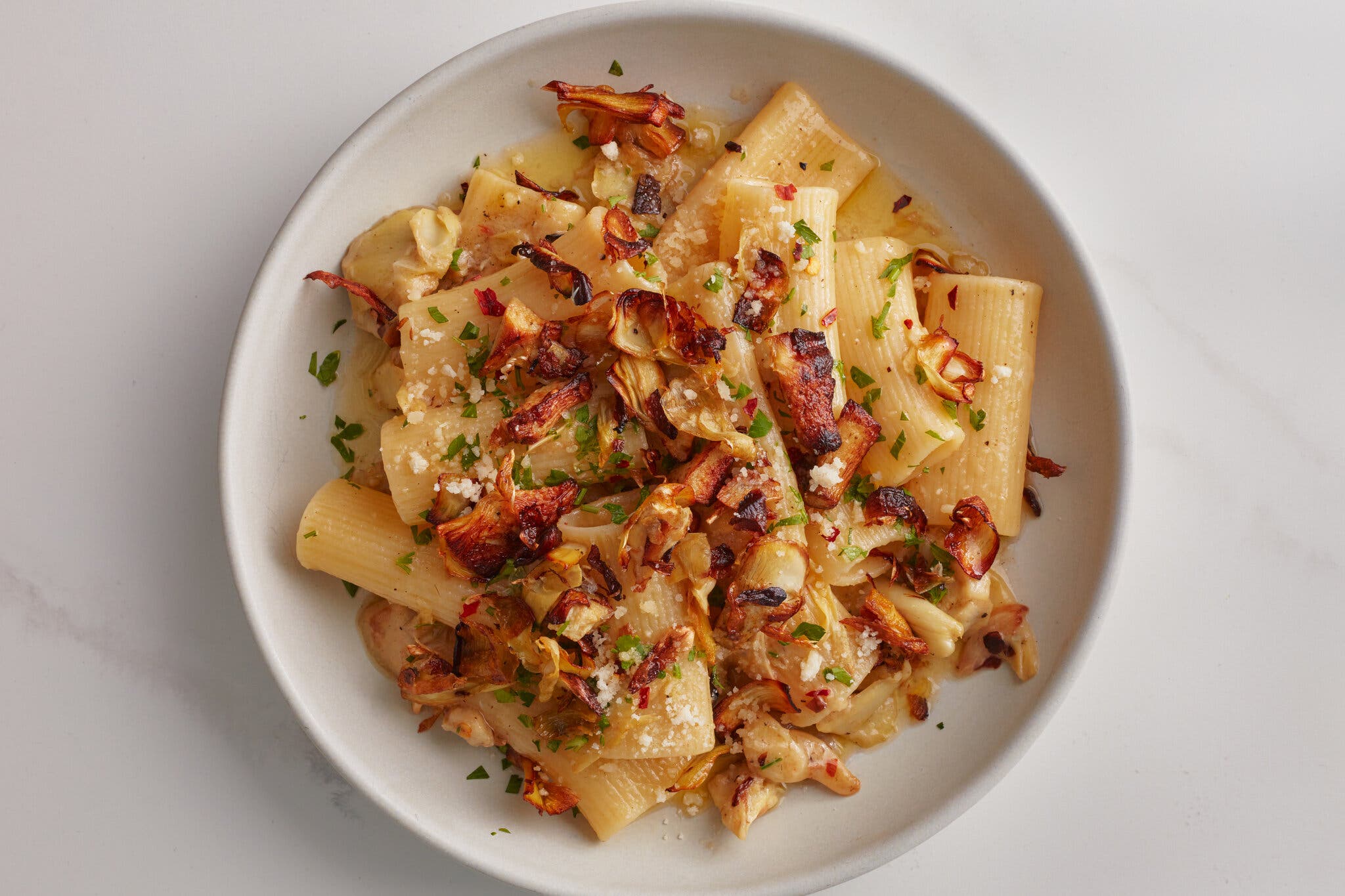 A single serving of creamy pasta is topped with crispy artichokes.