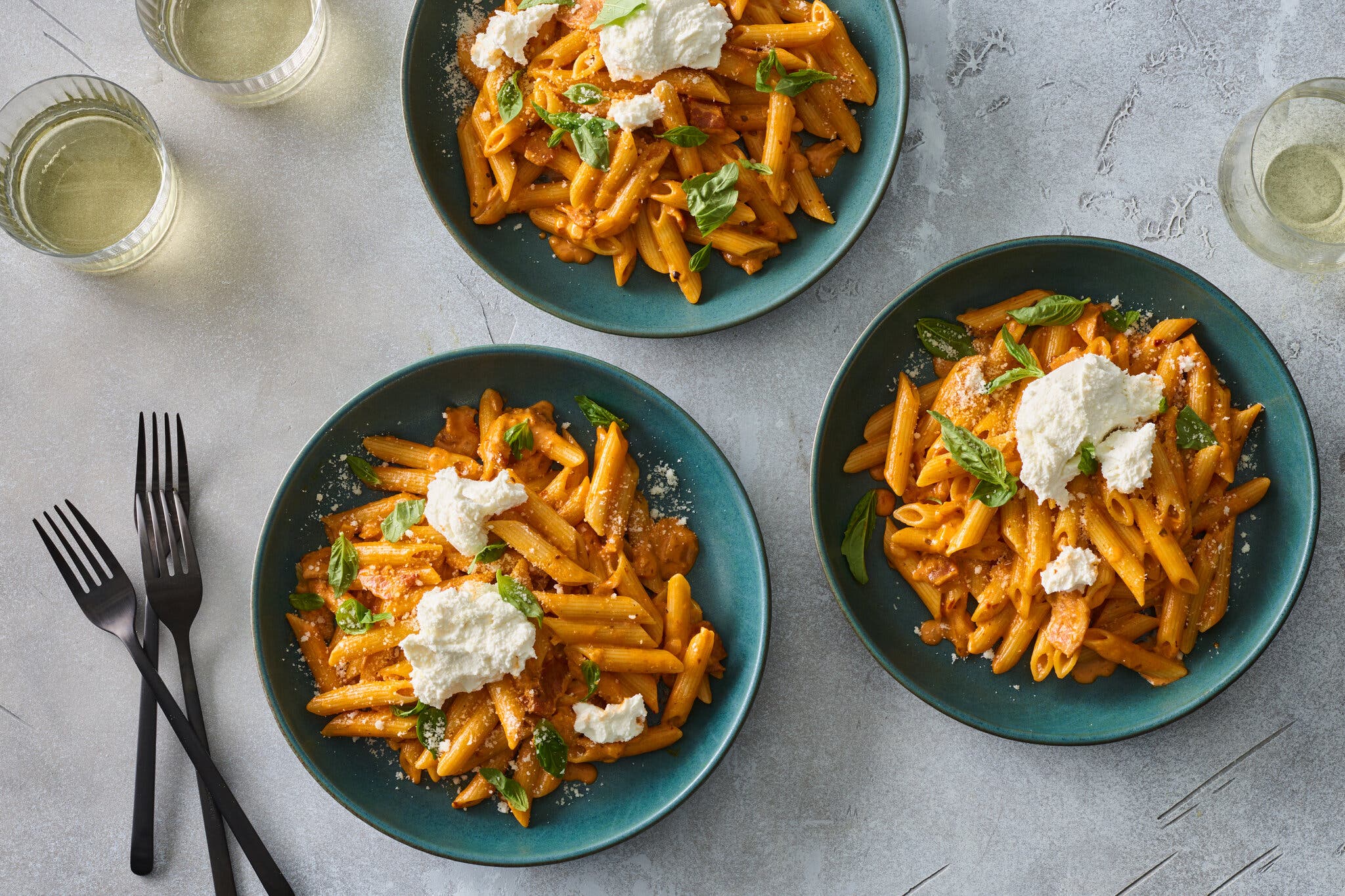 Three bowls of pasta in red sauce toppe with dollops of ricotta.