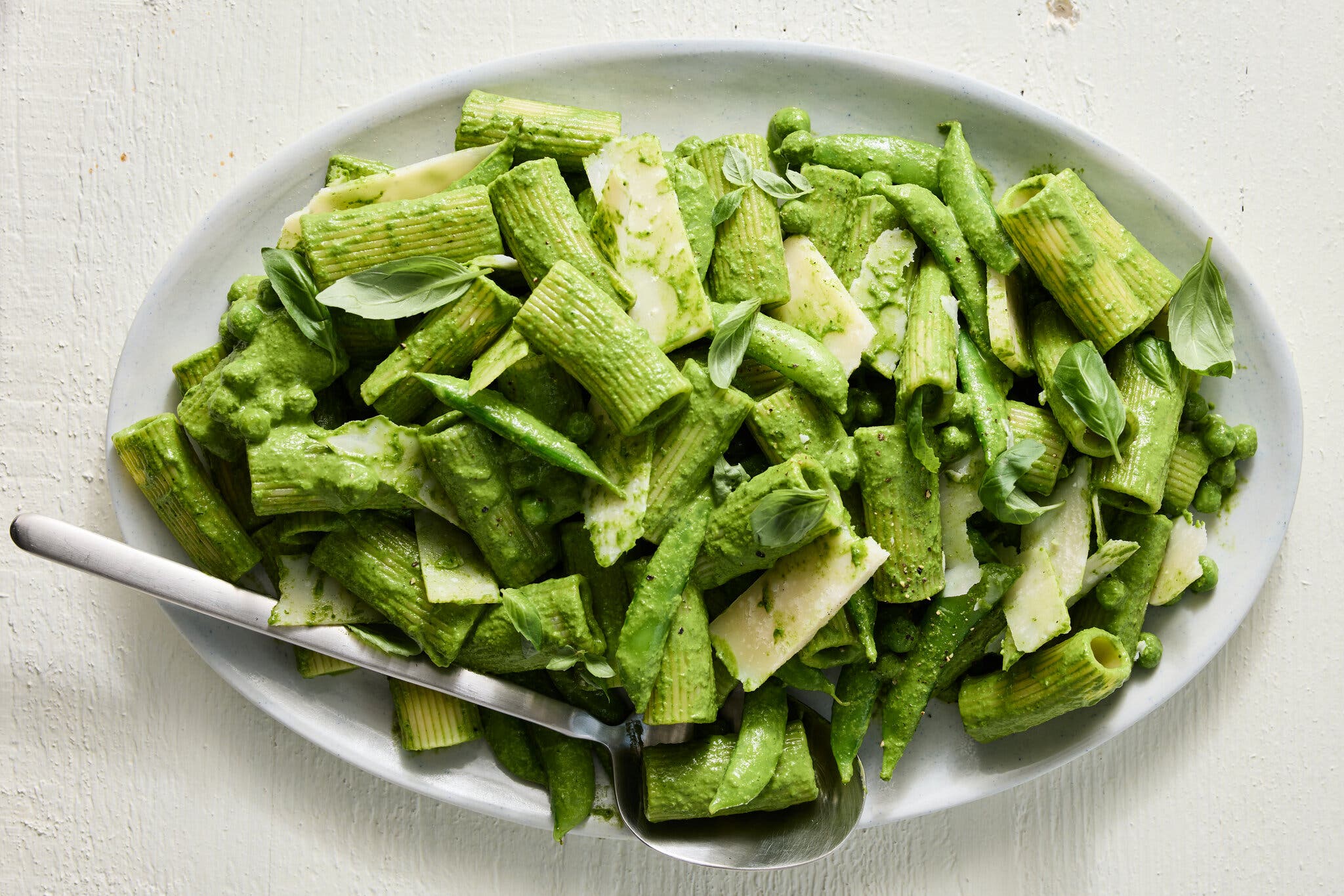 A platter topped with a green sauced pasta. 