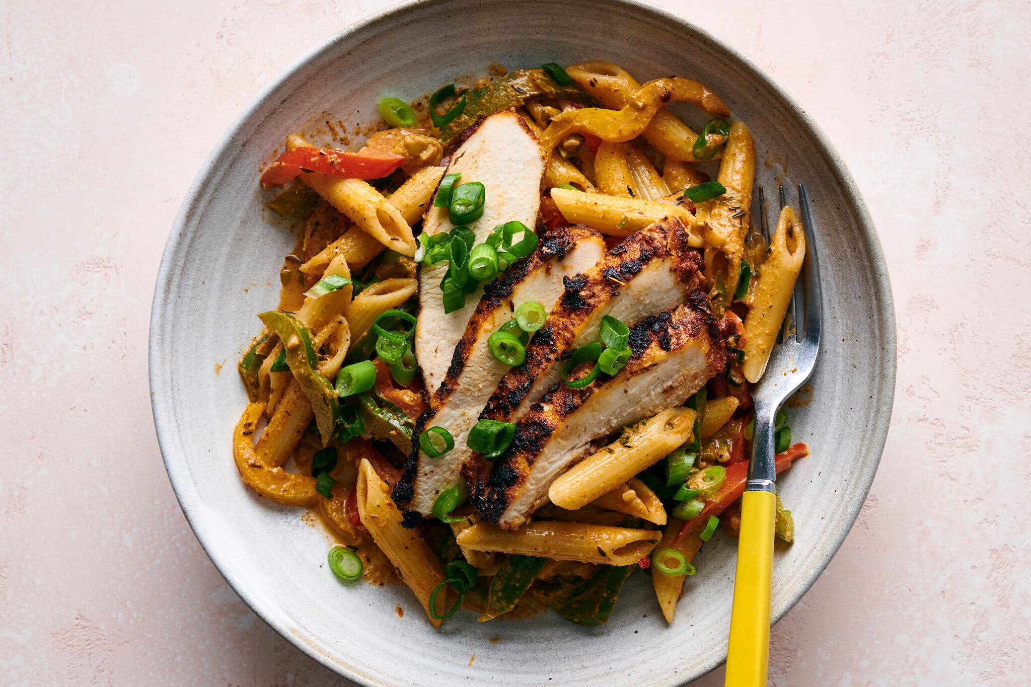 Short cut pasta with peppers, scallions, topped with pieces of blackened chicken breast.