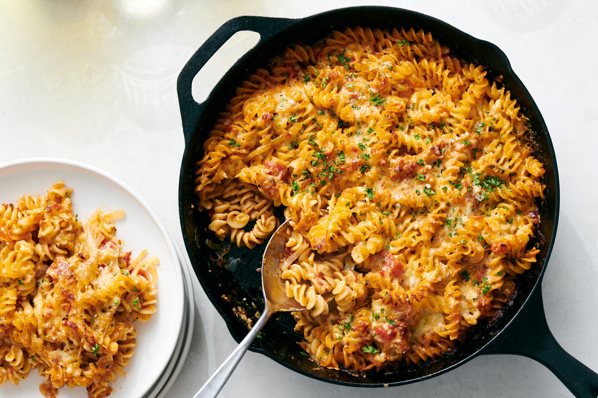 A golden baked pasta in a cast-iron skillet topped with Cheddar.