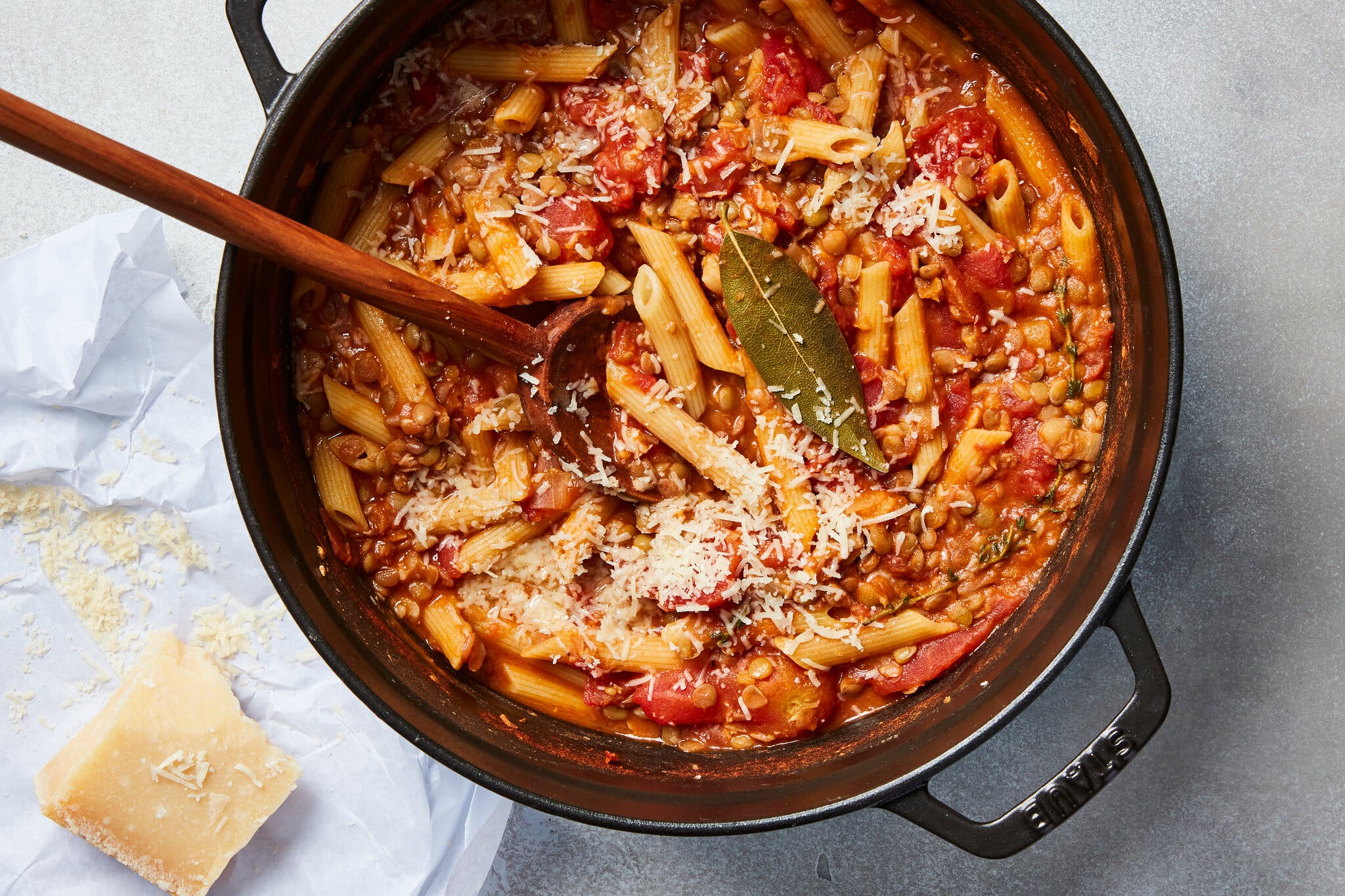 A skillet filled with pasta and lentils in a red sauce.