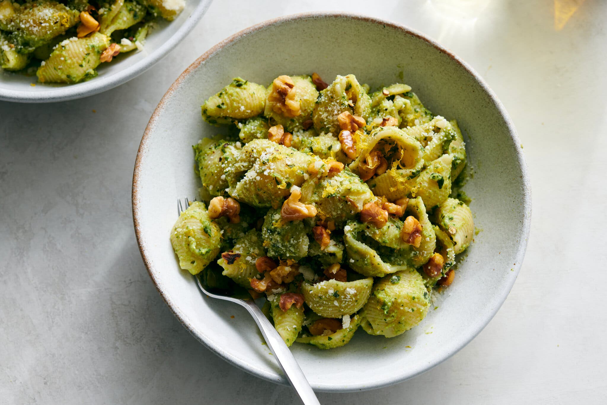 A white bowl filled with pesto tossed shells.