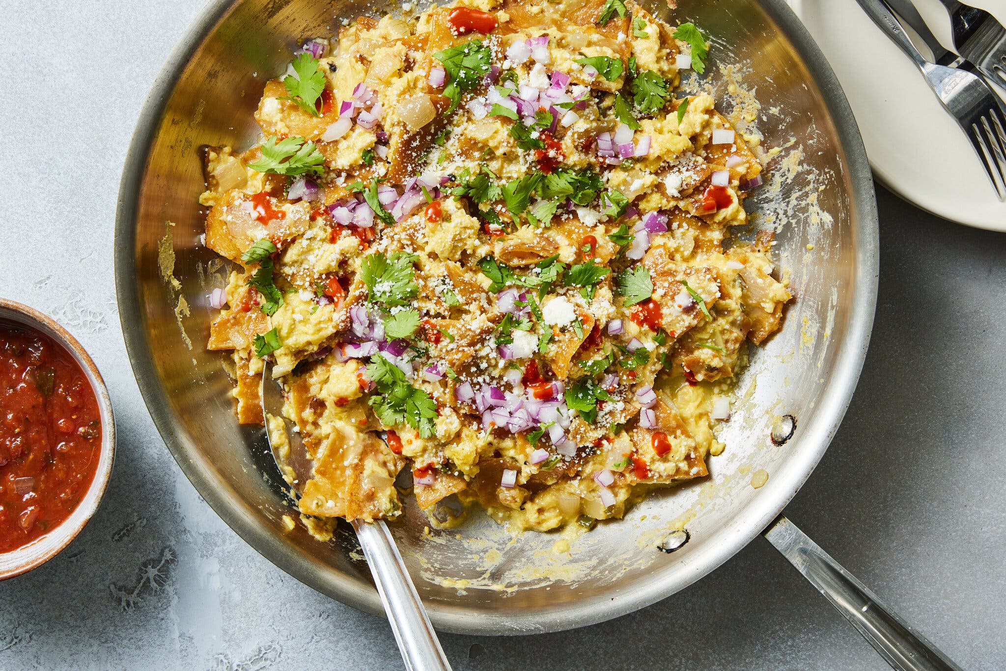 Scrambled eggs with torn flatbread, red peppers and onions in a skillet.