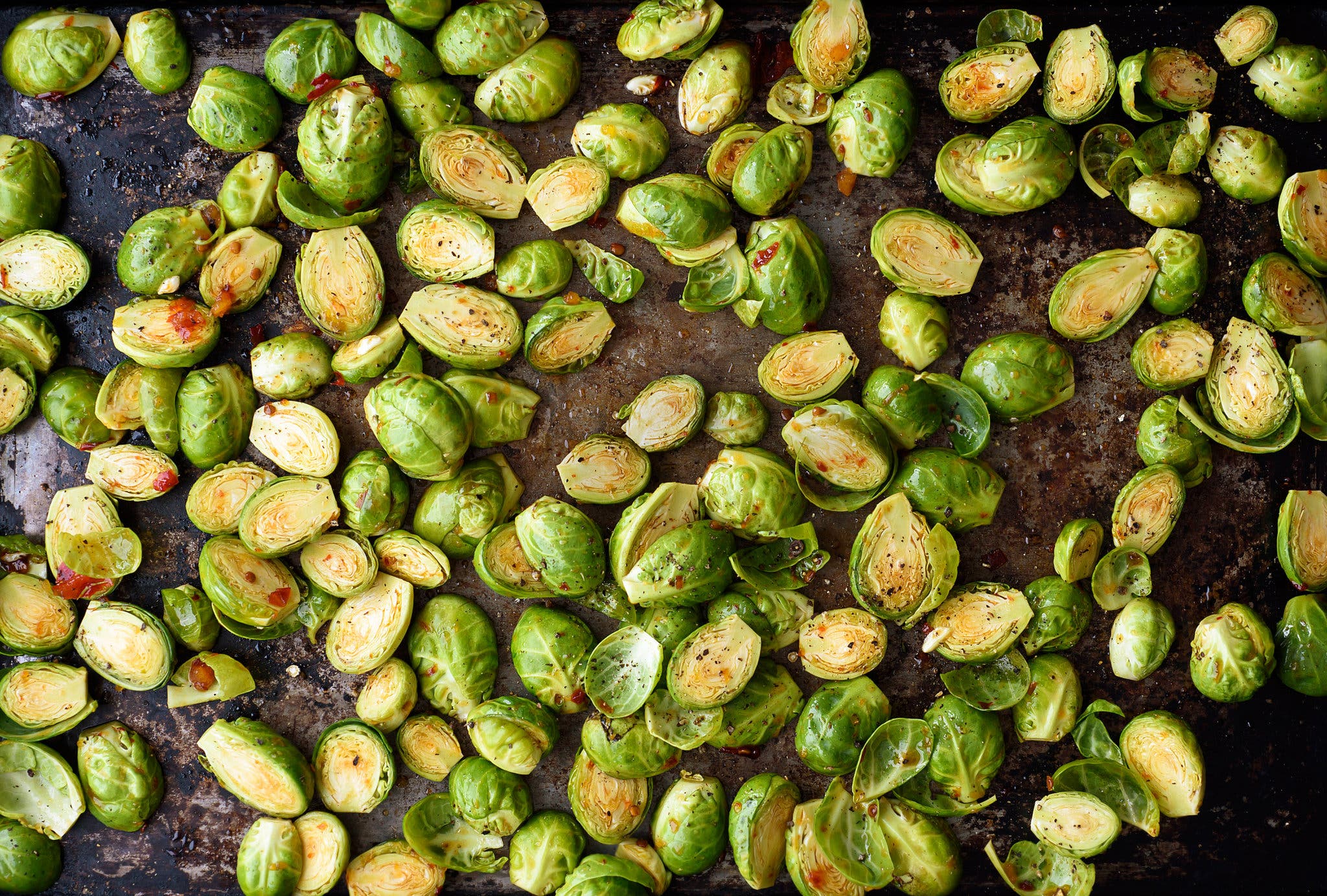 An overhead image of brussels sprouts roasting on a sheet pan.