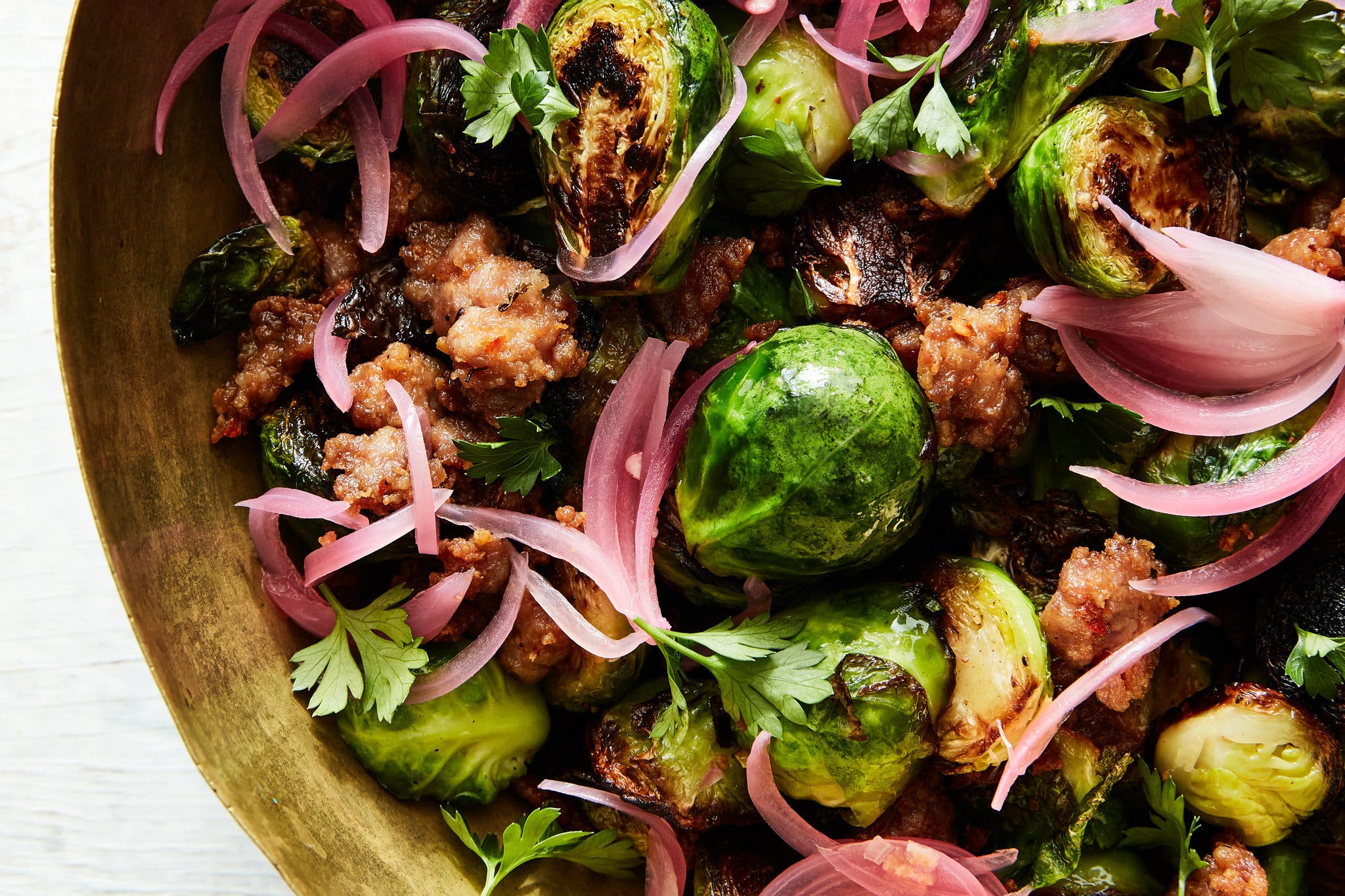 An overhead image of brussels sprouts, pickled red onions and sausage.