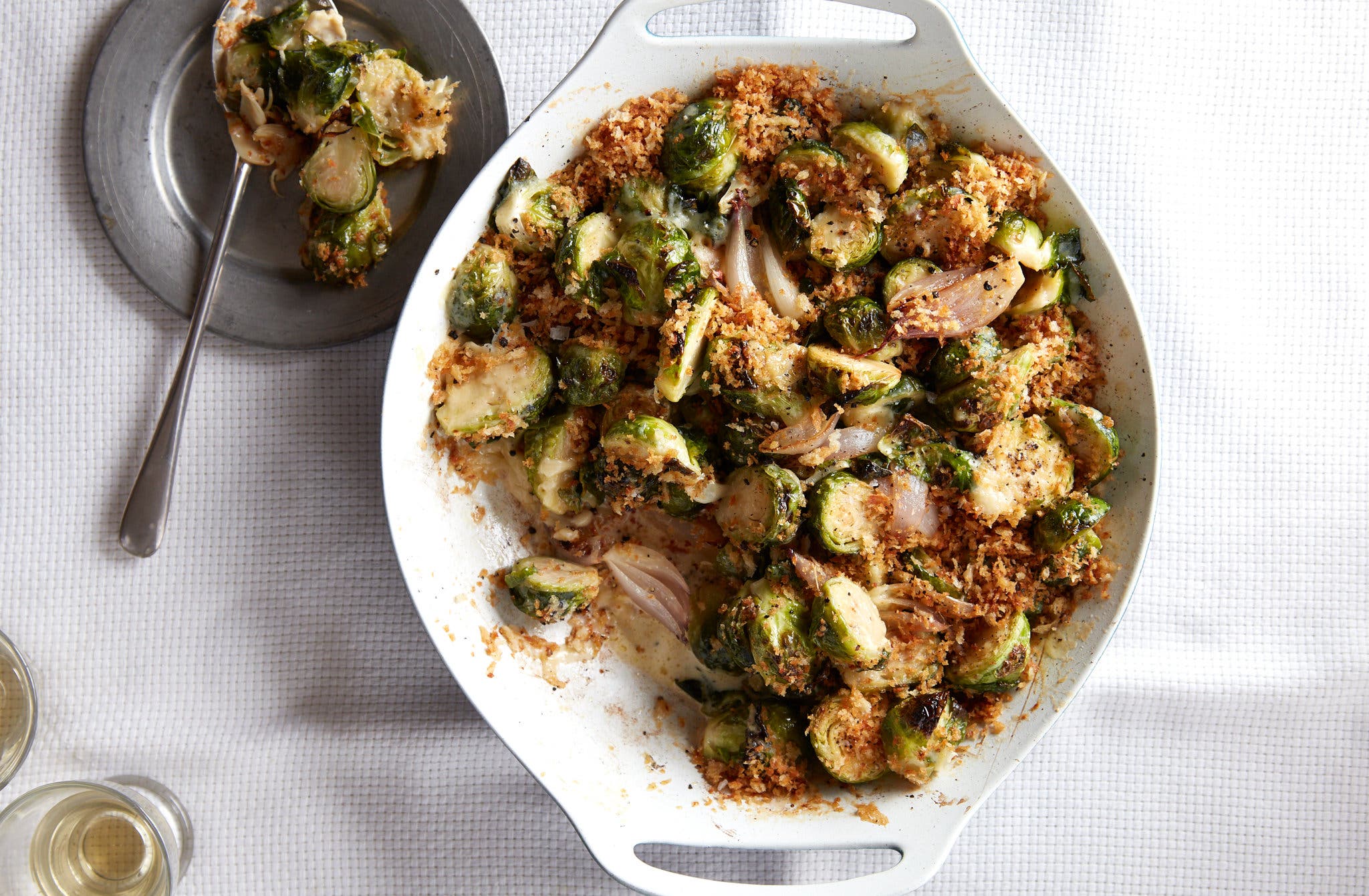 An overhead image of brussels sprouts in a baking dish scattered with bread crumbs.
