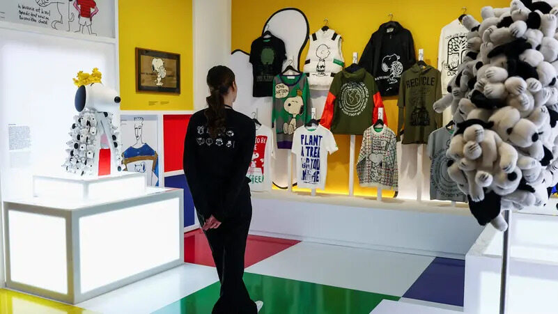 A woman views garments featuring Snoopy and Charlie Brown, showcased at the 'Snoopy in Style' exhibition in Paris on March 20, 2025, held to mark the 75th anniversary of the 'Peanuts' comic strip.