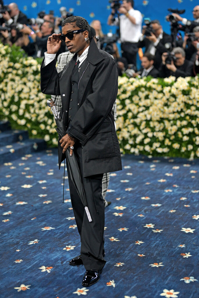 ASAP Rocky is wearing a black suit and holding an umbrella.