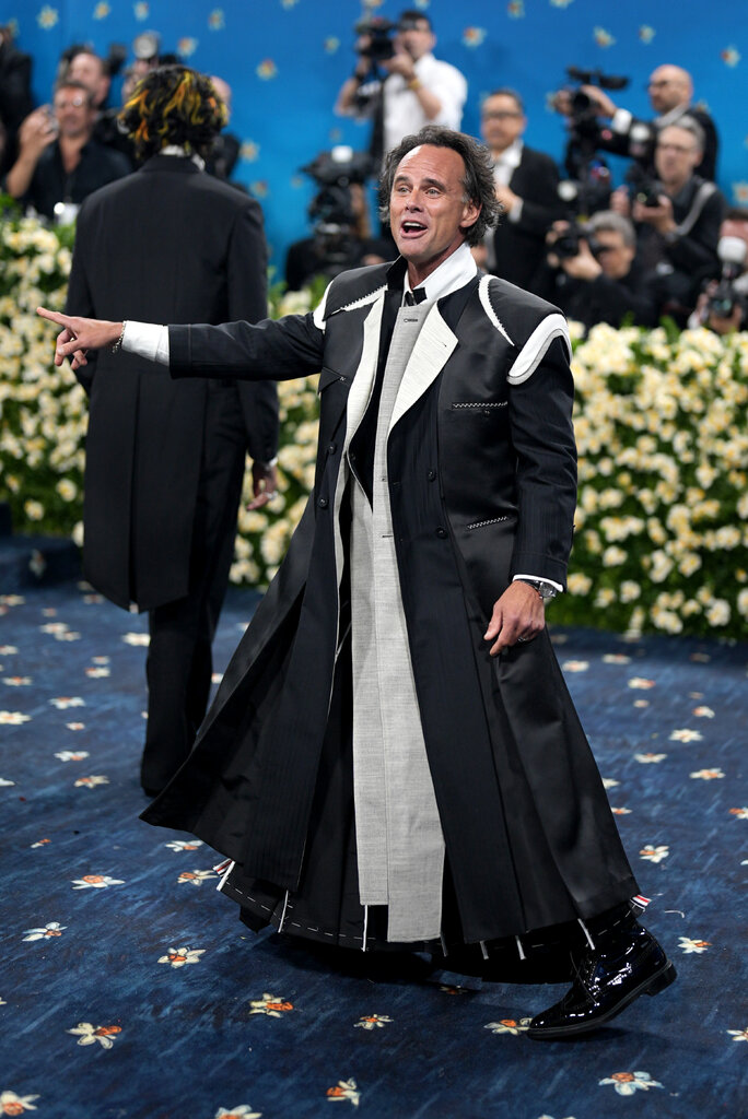 Walton Goggins is wearing a black suit with white details.
