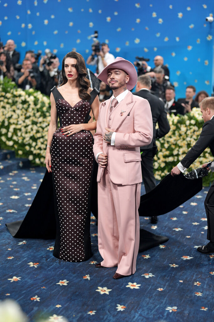 Valentina Ferrer is wearing a polka dot dress. J Balvin is wearing a light pink suit and matching hat.