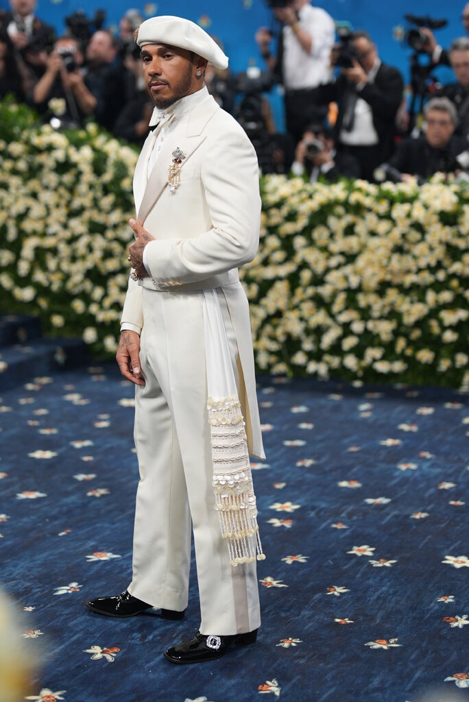 Lewis Hamilton wearing a cream suit and beret.