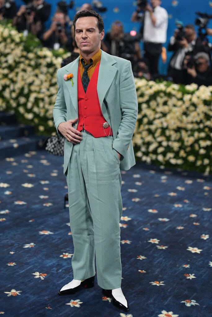 Andrew Scott wearing a turquoise green suit and red vest.