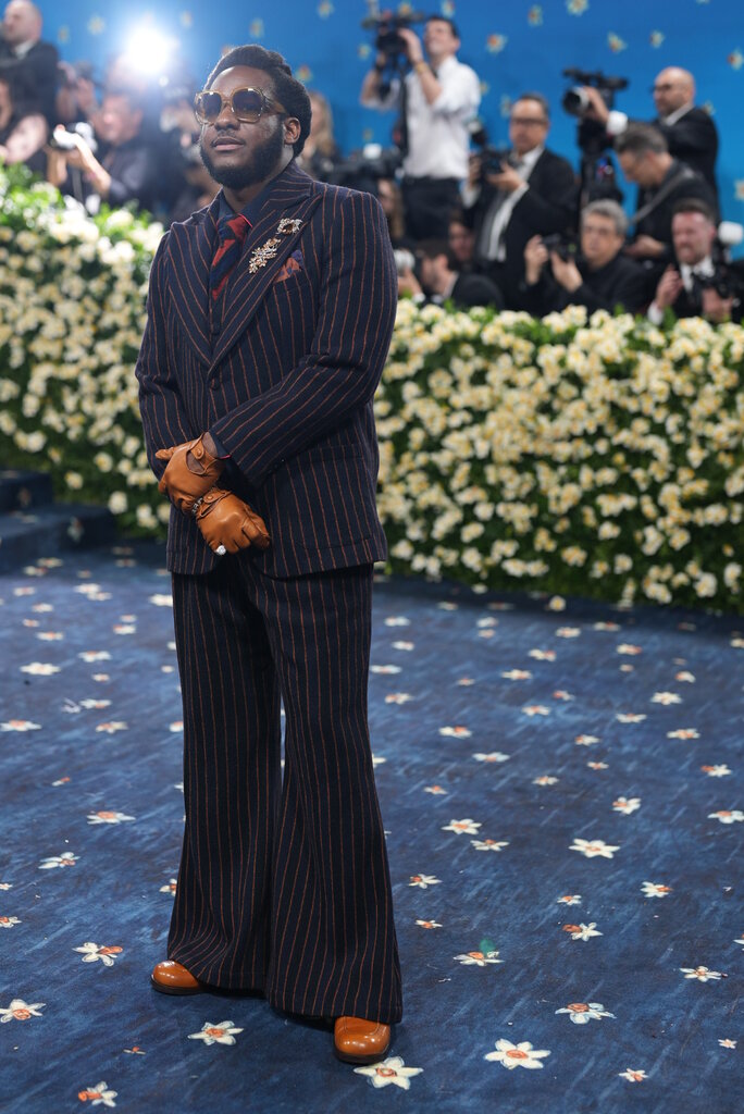 Spike Lee is wearing a black suit and orange and blue hat with matching sunglasses. Tonya Lewis Lee is wearing a blue gown that resembles a suit blazer.