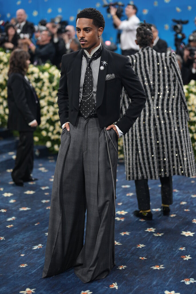 Keith Powers is wearing a suit with a polka dot tie and chain details.