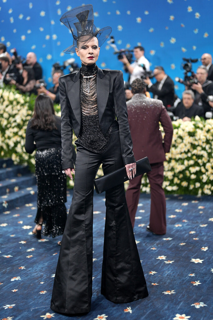 Jordan Roth wearing a sculptural, see-through top hat and suit with bell bottom pants.