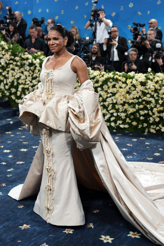 Audra Mcdonald wearing a beige gown with embellished flowers down the front and a voluminous peplum waistline.