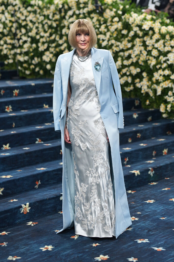 Anna Wintour is wearing a silver embroidered gown with a light blue blazer.