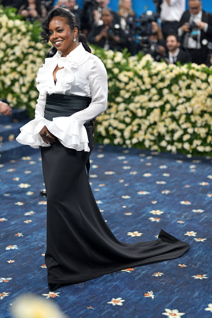 Adrienne Warren wearing a ruffled white blouse and long black skirt.
