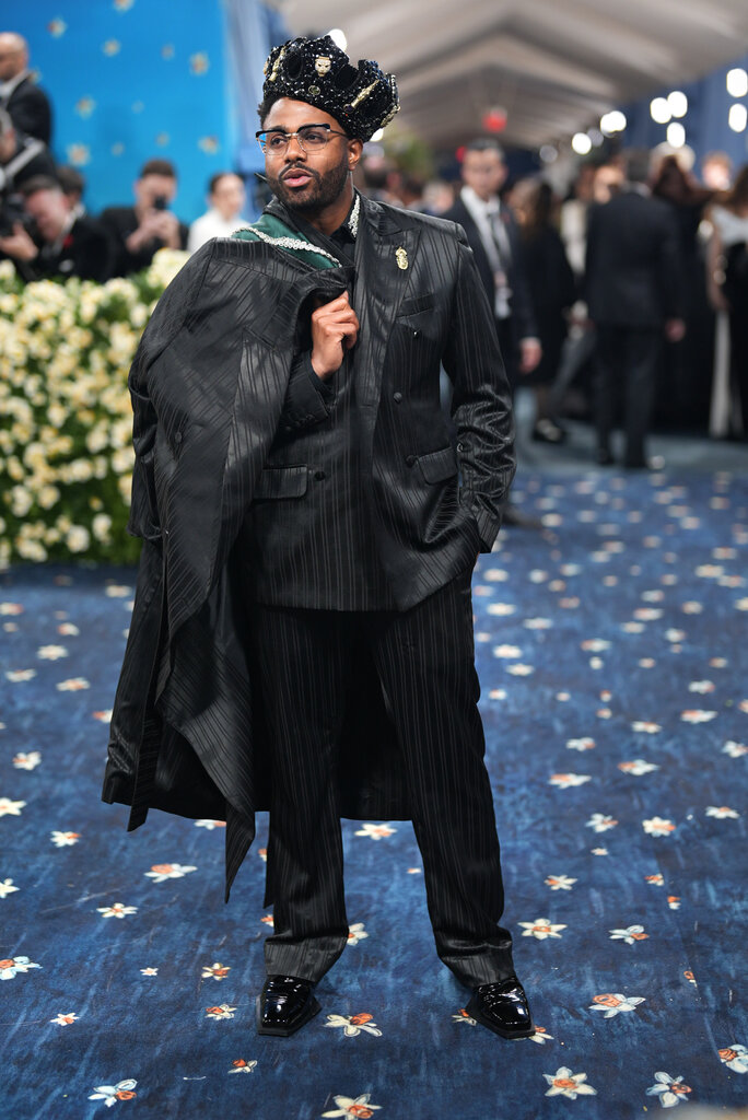 Kwame Onwuachi wearing a shiny, striped suit and black crown.