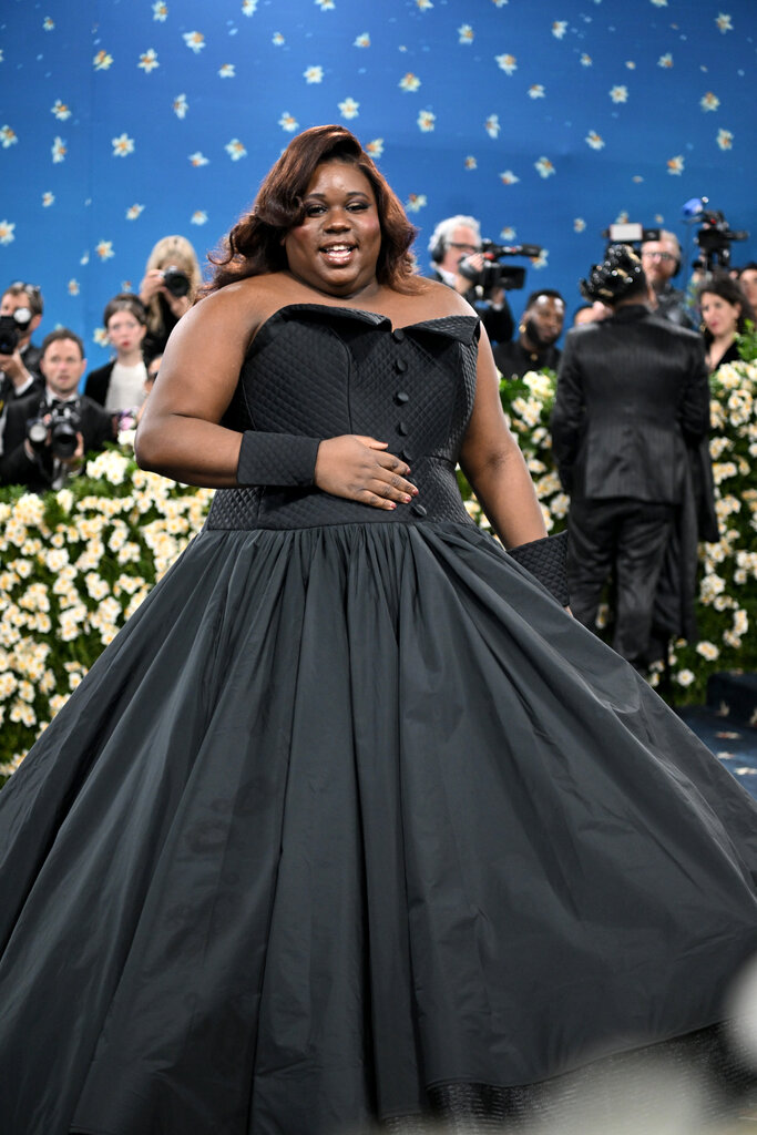 Alex Newell wearing a black strapless gown with coordinating tuxedo cuff bracelets.