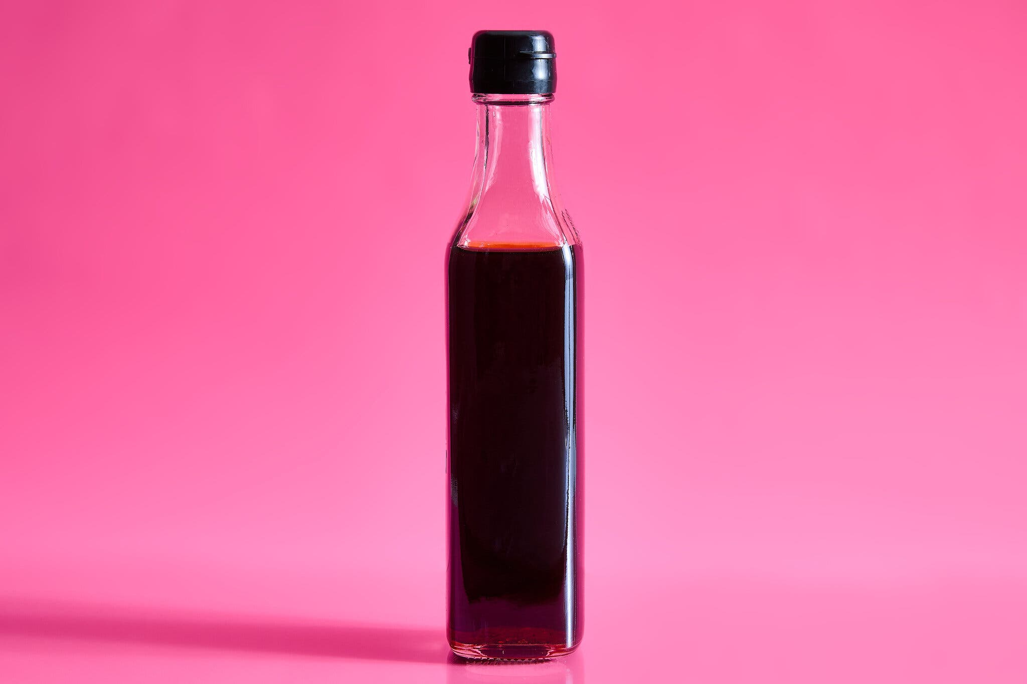 A bottle of fish sauce against a hot pink background.