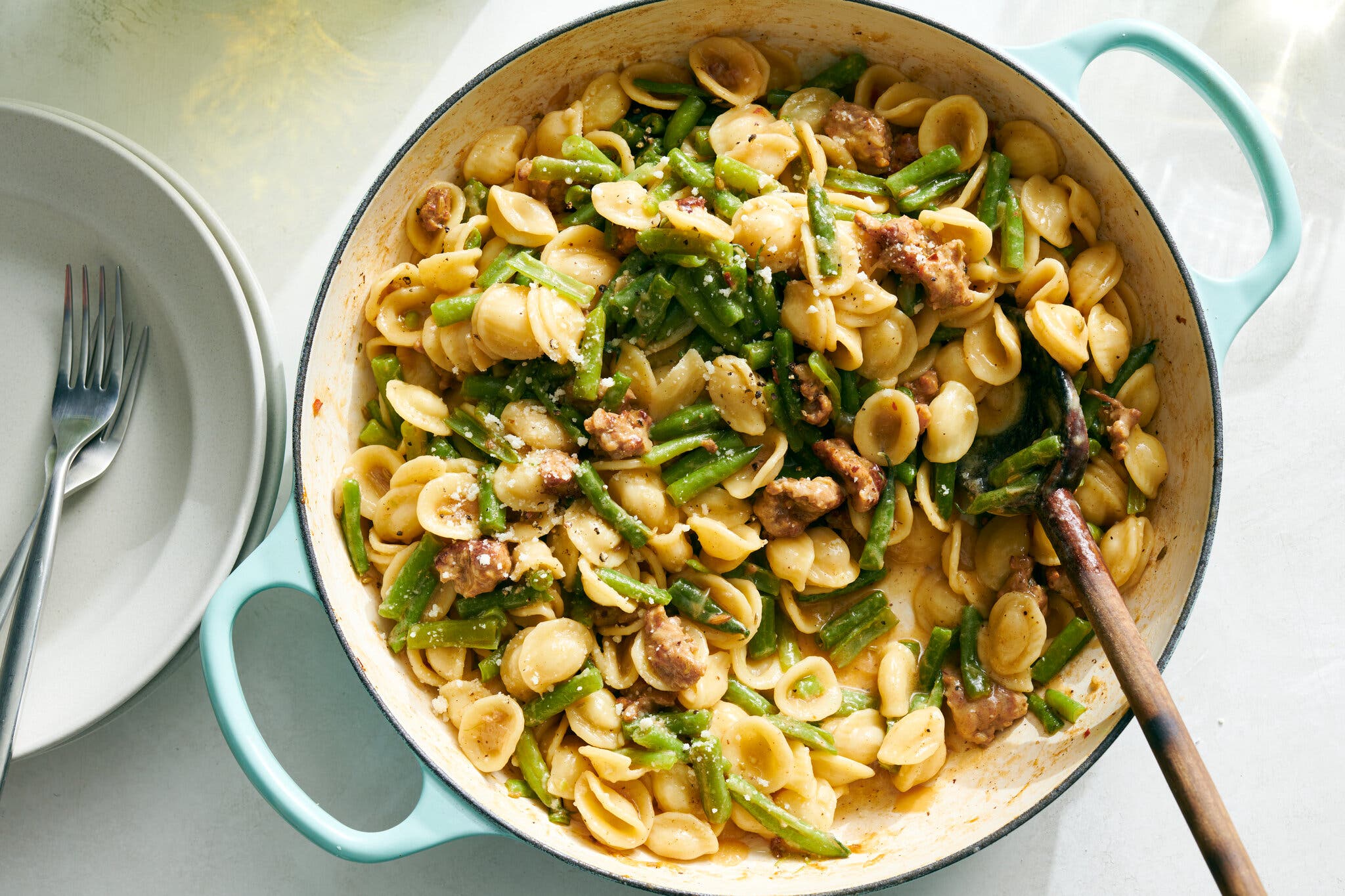 A pot of pasta, green beans and sausage.