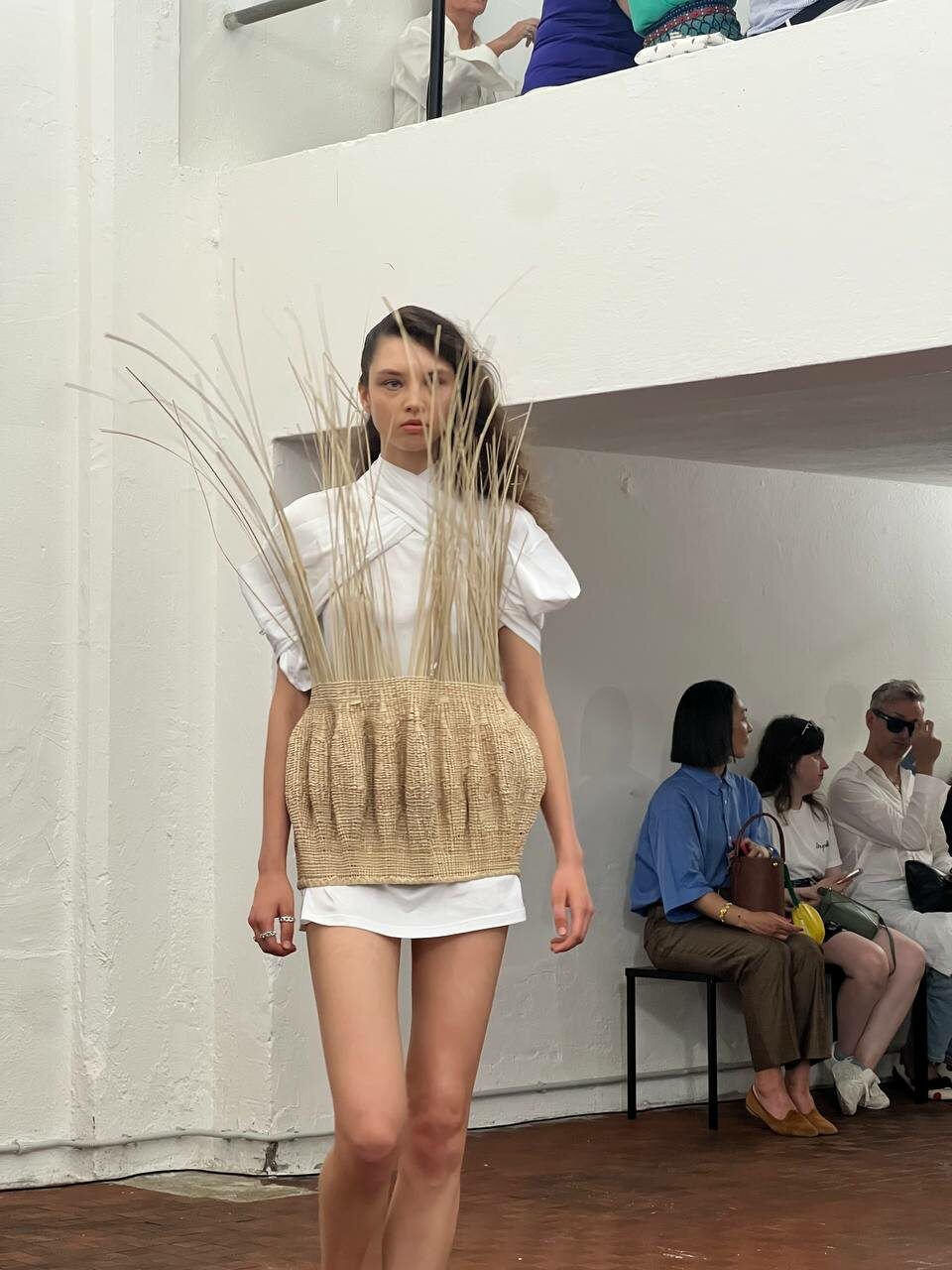 A model in a mini-tunic dress wrapped in a basket-inspired woven piece, echoing Zimbabwean craftsmanship.