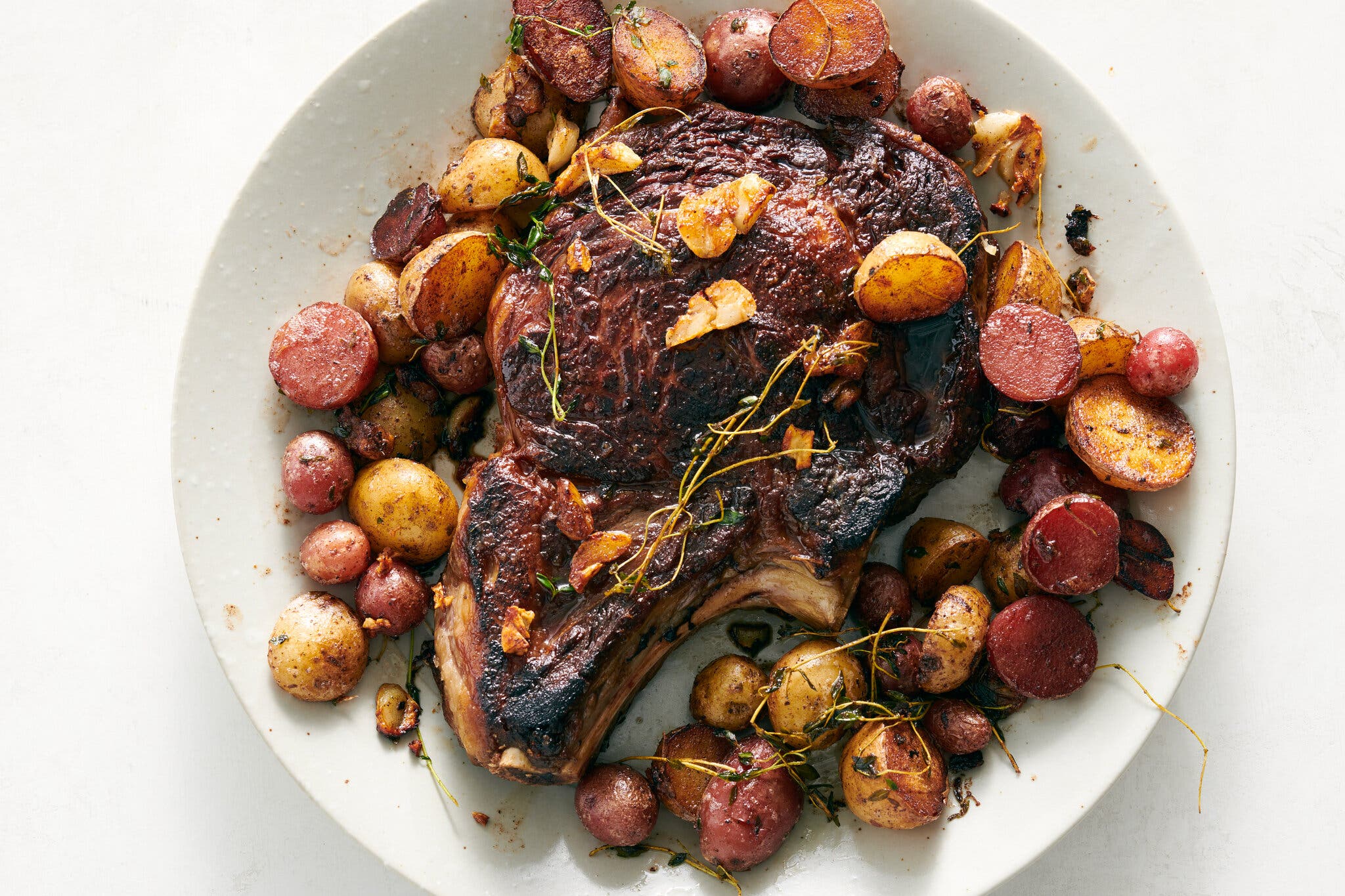 Buttery steak and potatoes are shown on a white plate.