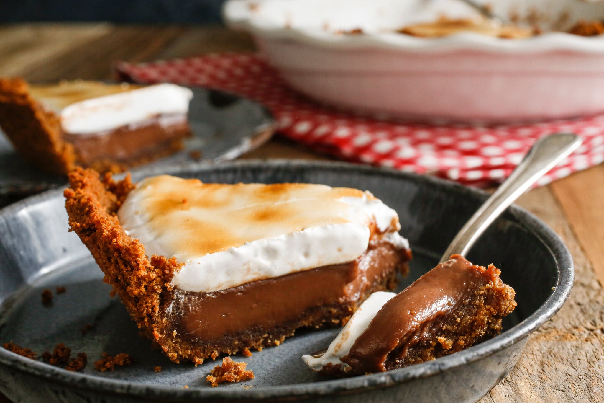 A slice of s’mores pie with a graham cracker crust, chocolate pudding center and lightly toasted marshmallow topping.