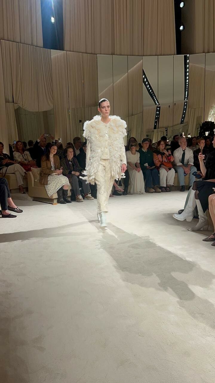 A feather-embellished ivory ensemble adds softness and volume to Chanel’s nature-inspired silhouettes.