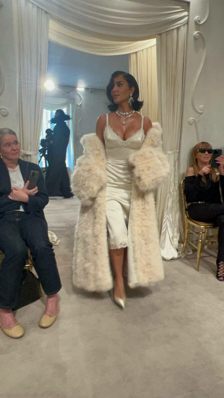 Kim Kardashian in ivory slip dress and faux fur coat.