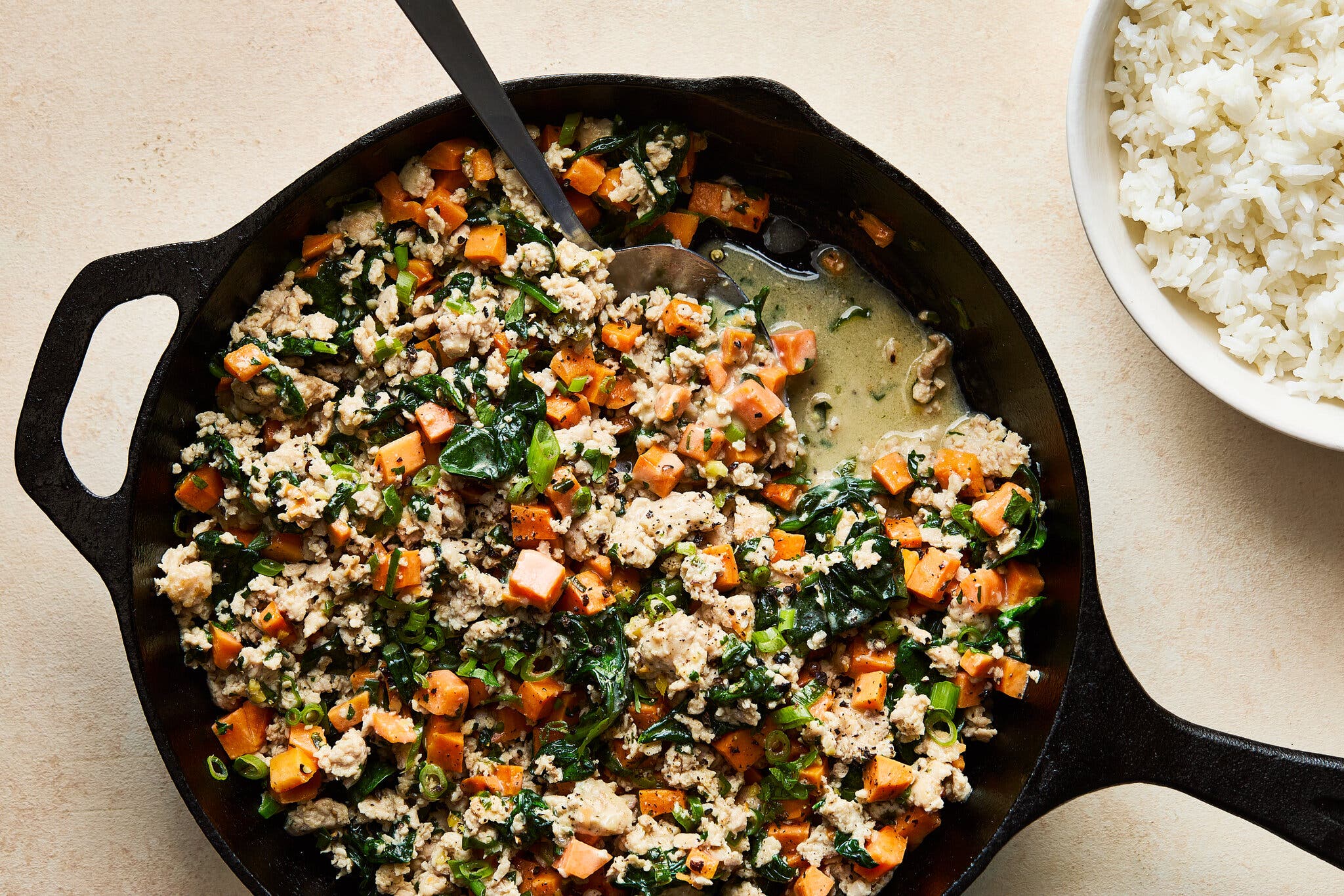 An overhead image of ground chicken and cubed sweet potatoes in a cast-iron skillet.