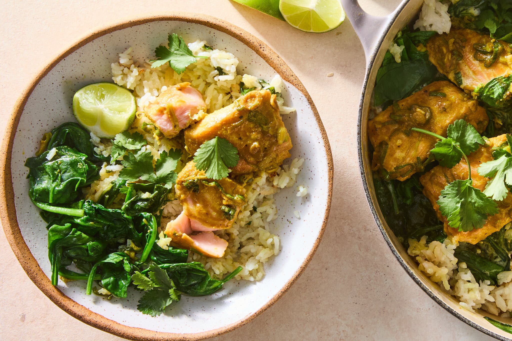 An overhead image of salmon and greens on top of a bed of rice next to a Dutch oven.