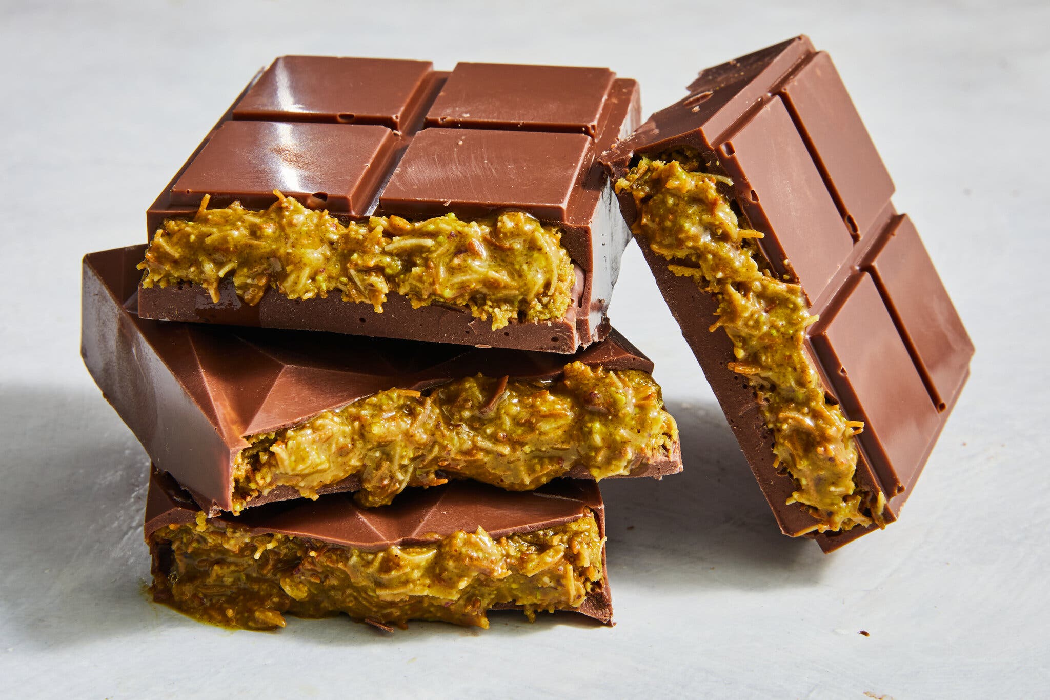 Halved Dubai chocolate bars are stacked to reveal their creamy olive green insides.