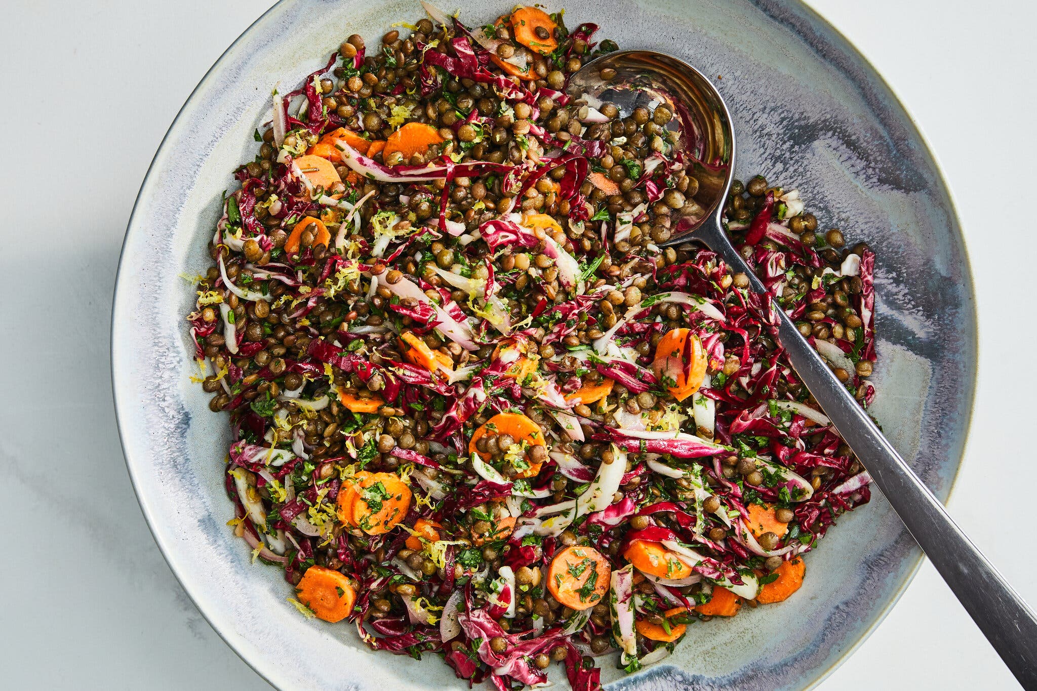 An overhead image of a swirled bowl topped with lentils, carrots and cabbage.