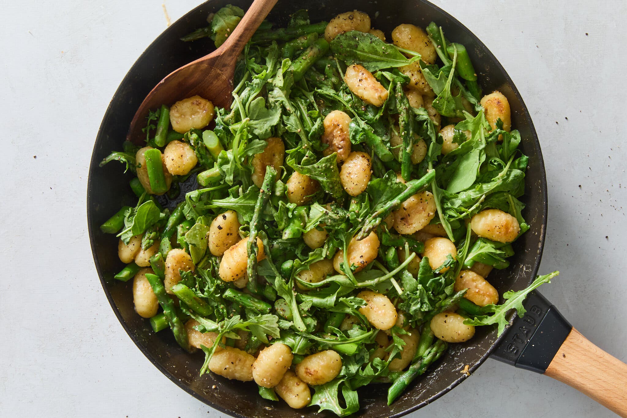 An overhead image of a skillet filled with crisp gnocchi and greens.
