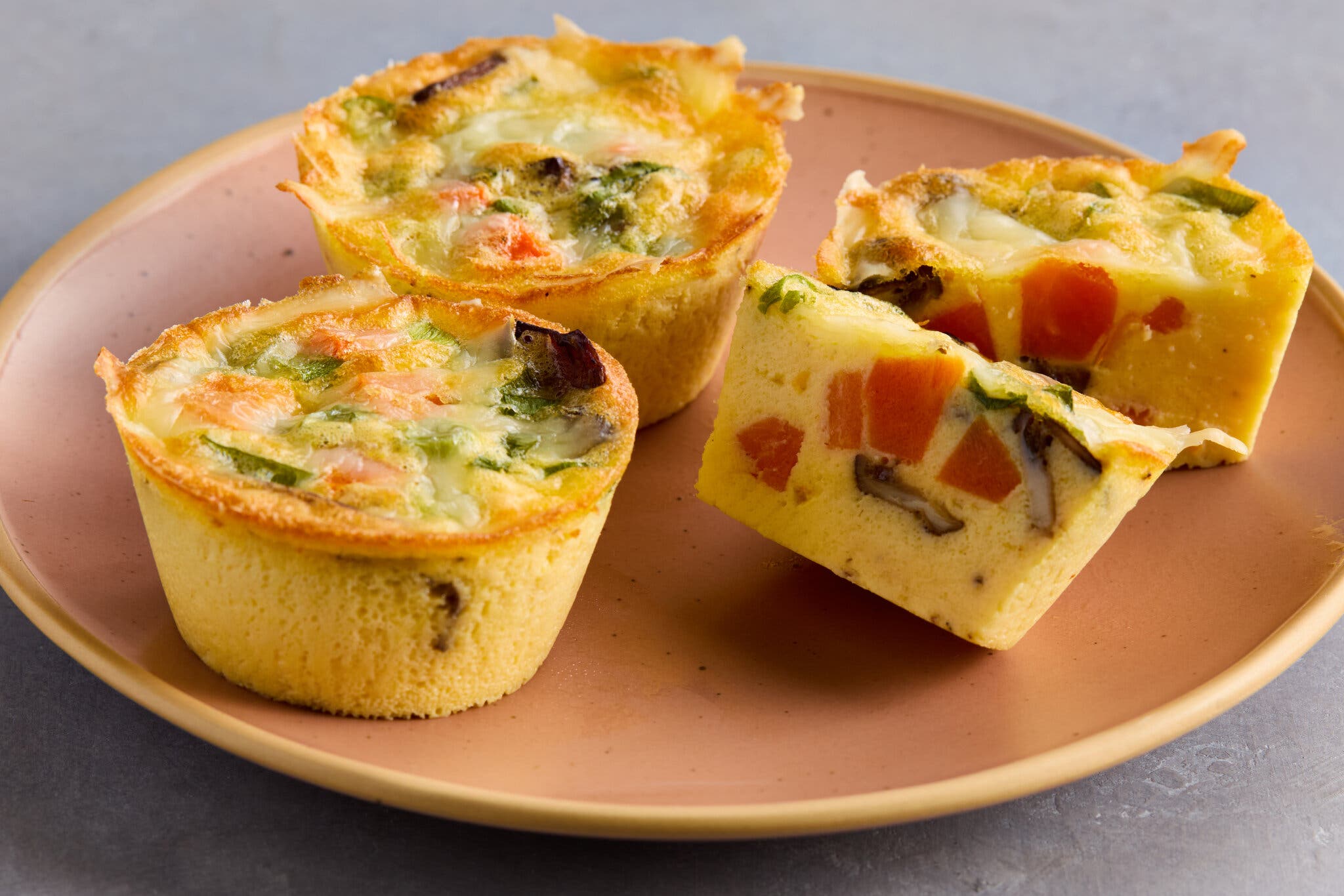A side image of cottage cheese egg bites on a plate. One is halved to show its insides.