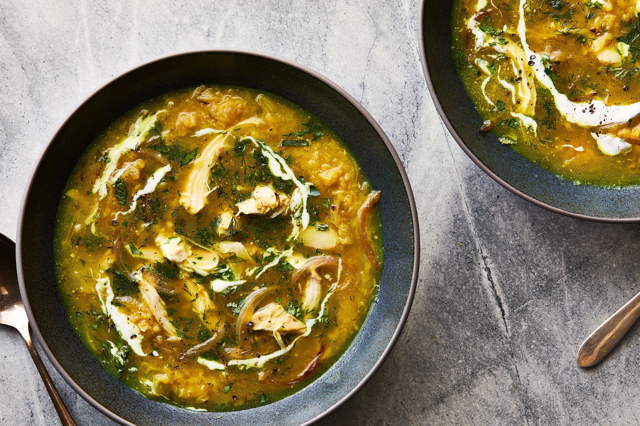 An overhead image of two bowls of chicken and red lentil soup.