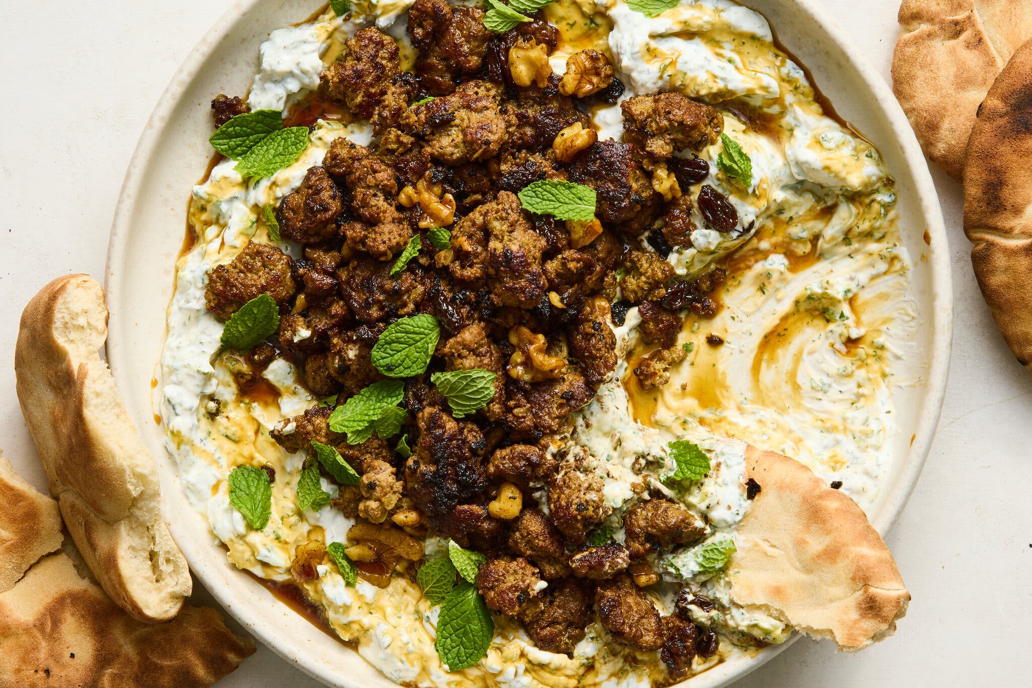 An overhead image of a plate topped with ground beef over a creamy cucumber yogurt.