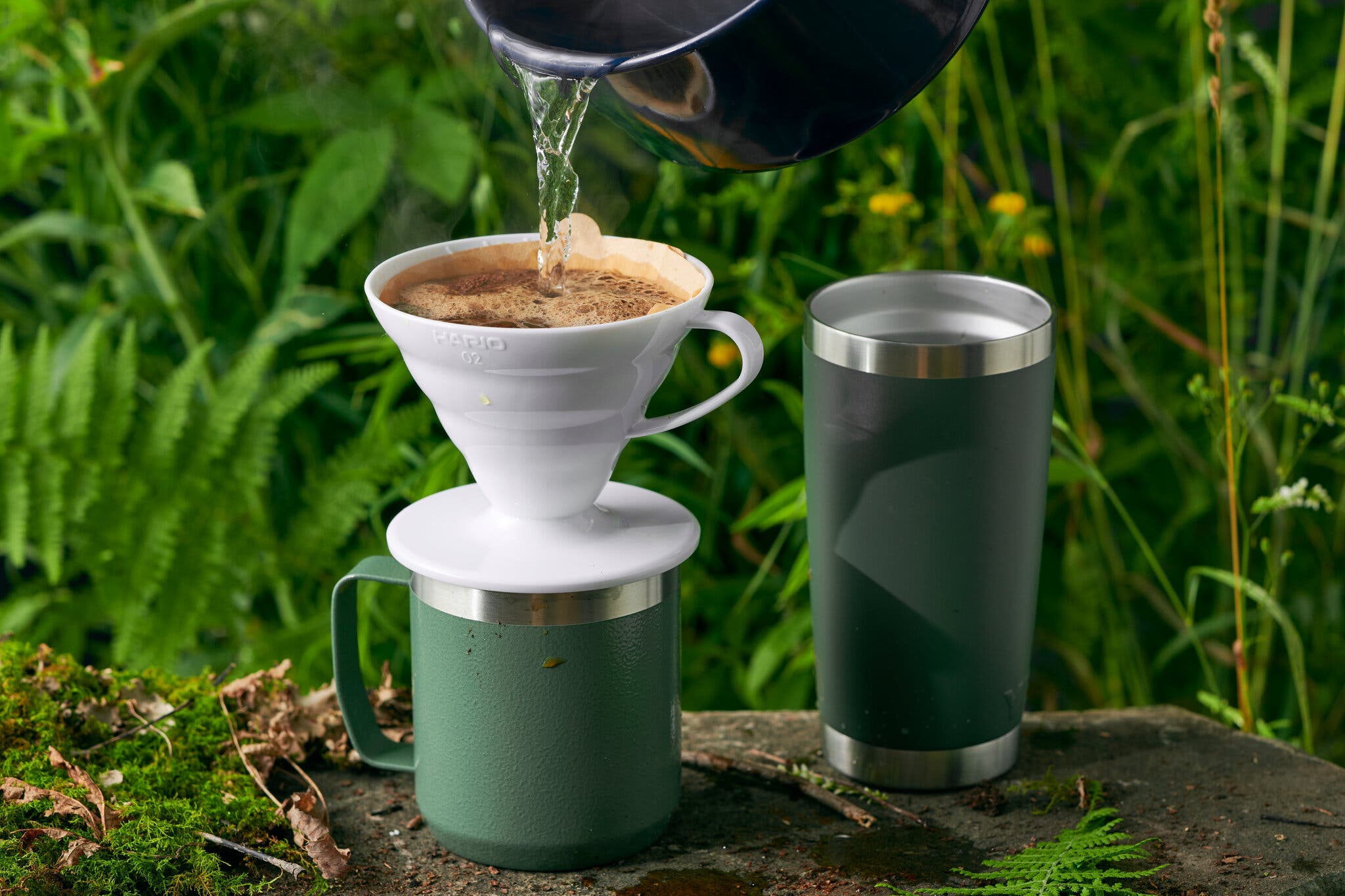 A side image of a pour-over coffee maker set over a mug. Hot water is poured into the mug from the top of the frame.