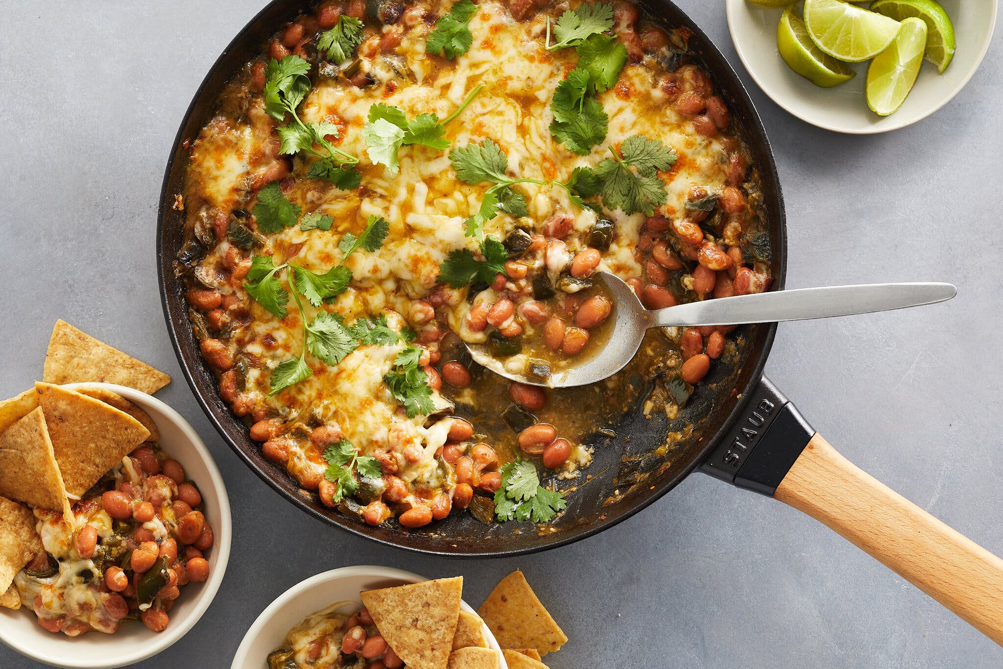 An overhead image of a cast-iron skillet filled with cheesy beans.