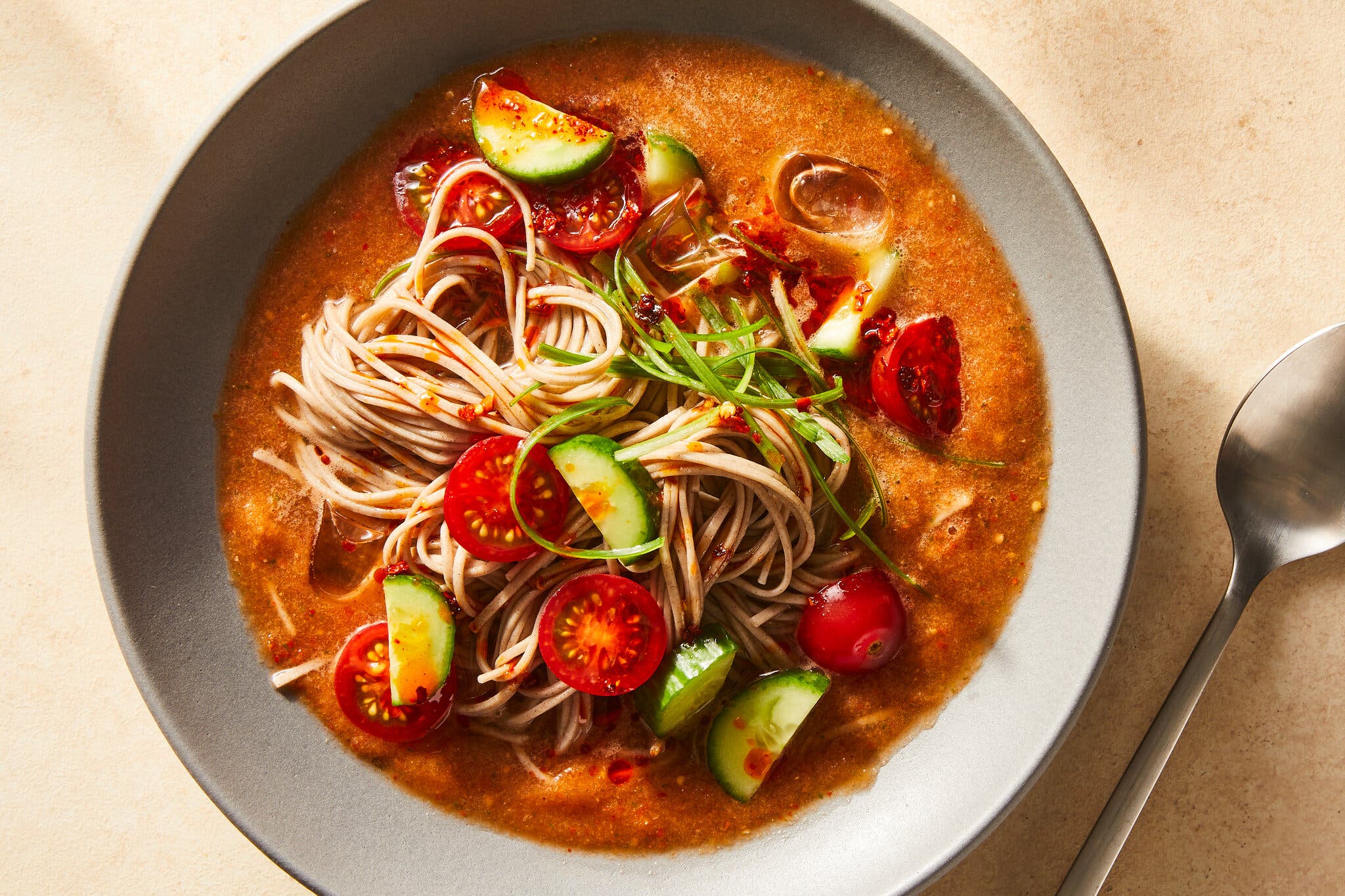 An overhead image of a noodle soup in a red broth.