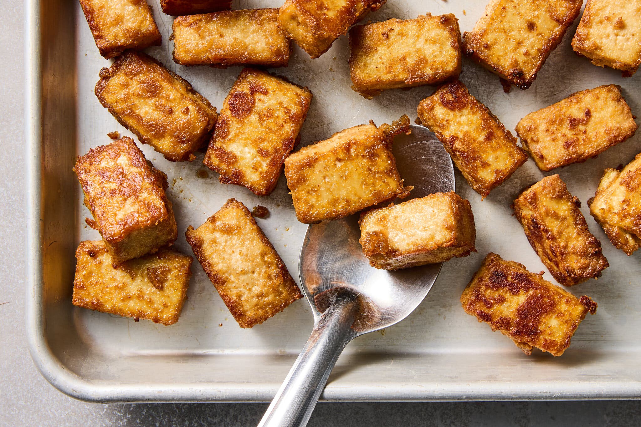 An overhead image of several cubes of tofu with browned bits and crispy edges. 
