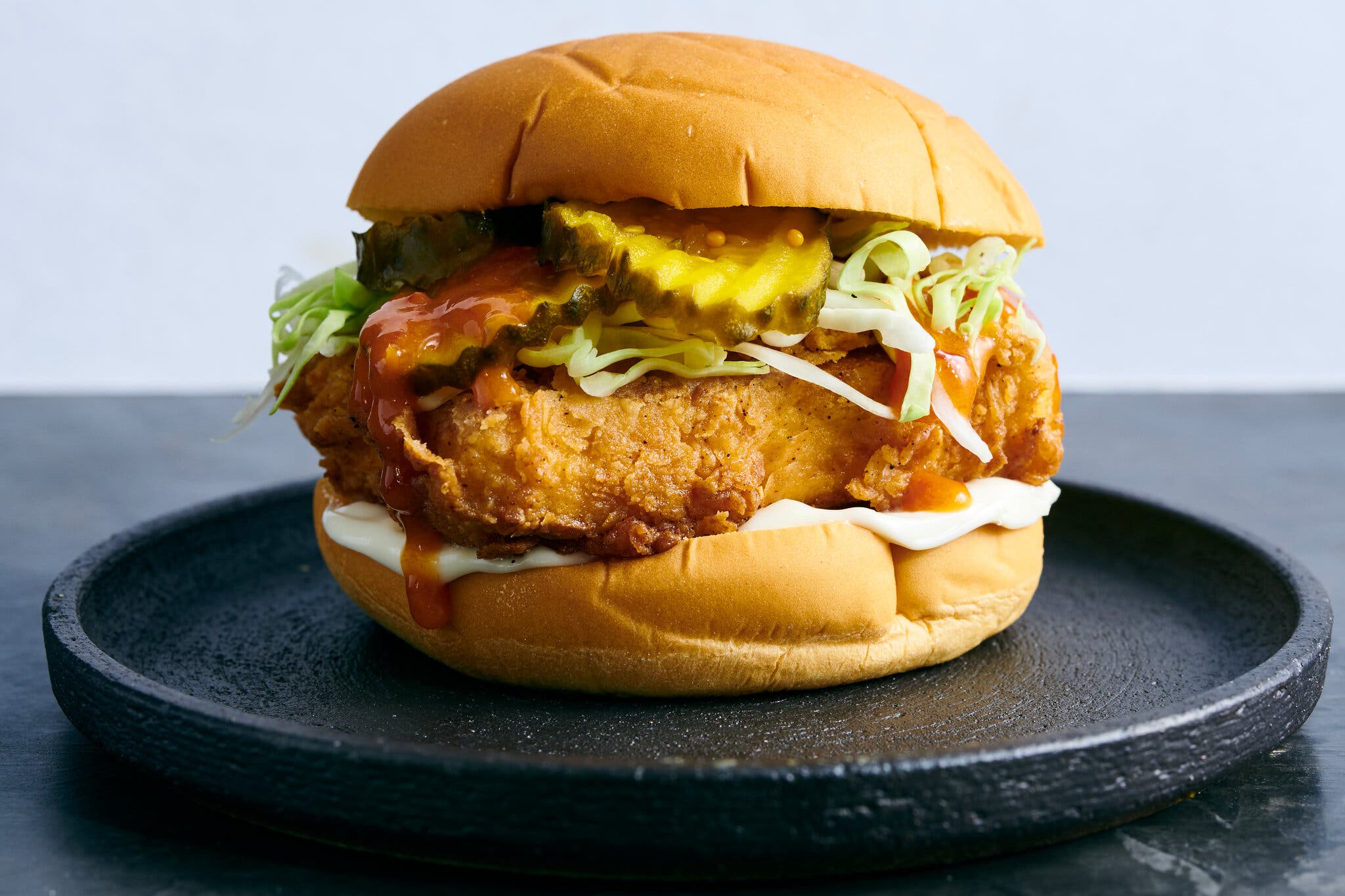 A side image of a fried tofu sandwich piled high with toppings.