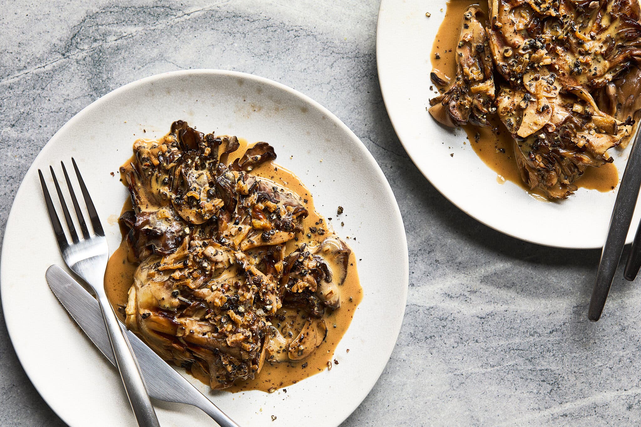 An overhead image of two servings of saucy mushrooms.